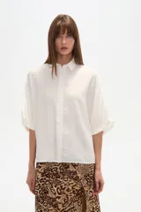 Camisa de viscosa color blanco, de corte holgado, con cuello clásico y cierre frontal de botones. Presenta mangas cortas con diseño amplio.