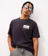 Remera de algodón color gris oscuro con cuello redondo y manga corta. Presenta un diseño gráfico en la espalda con la ilustración de un automóvil clásico, tipografía estilo vintage y detalles decorativos.