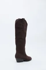 Bota texana de caña alta confeccionada en gamuza negra, con diseño de estilo western, costuras decorativas, tirador superior y taco bajo levemente inclinado.