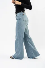 Jean de corte campana con tiro medio, confeccionado en denim con elastano. Presenta un lavado claro y ruedo deshilachado.
