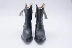 Botas estilo texanas de caña media, confeccionadas en cuero con estampado animal print tipo vaca en blanco y negro. Presentan un diseño de punta fina y taco cuadrado.