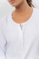 Remera manga larga color beige melange, confeccionada en algodón con spandex, con escote redondo y cartera delantera con botones y detalle de cordón tejido multicolor.