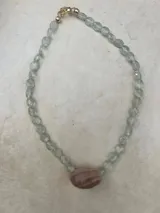 Collar largo de cuentas de piedras semipreciosas en tonos tierra, con dijes de conchas marinas.