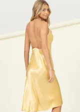 Vestido corto de satén color dorado con cuello drapeado y breteles finos. Presenta un corte recto y fluido, ideal para eventos formales o nocturnos.