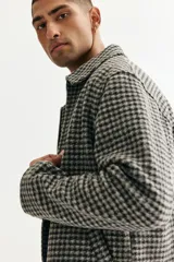 Sobrecamisa de fieltro con estampado de cuadros en tonos grises, cuello clásico, cierre bidireccional y bolsillos insertados en la parte delantera. Presenta un corte regular fit y no tiene forro.