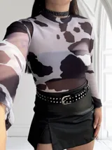 Body de tul traslúcido con estampado de manchas de vaca en blanco y negro, cuello alto y mangas largas.