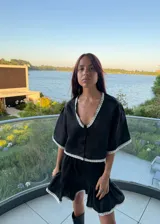 Falda corta de lino color negro, con diseño acampanado y detalle de puntilla blanca en el ruedo.