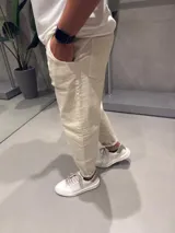 Jean de corte slouchy en color beige, confeccionado en denim de algodón. Presenta un diseño de tiro medio con ajuste holgado en la cadera y muslos, estrechándose hacia los tobillos.