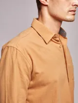 Camisa de manga larga confeccionada en tejido de franela de algodón con un toque de spandex. Presenta cuello clásico, cierre frontal con botones y un bolsillo en el pecho.