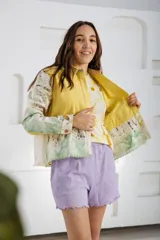 Chaqueta color beige con estampado abstracto en tonos amarillos, con cuello camisero, cierre frontal con botones, bolsillos plaqué y puños camiseros.