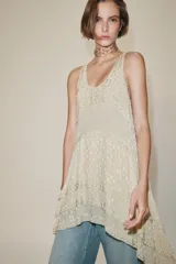 Vestido corto de viscosa color crudo, con escote redondo, manga sisa y diseño en jacquard con aplicaciones de abalorios. Presenta múltiples paneles superpuestos y bajo asimétrico.
