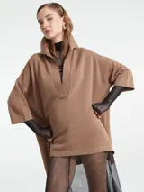 Poncho tejido de punto color negro con escote en V y cuello tipo polo. Presenta un diseño holgado con mangas tres cuartos.