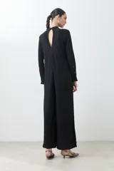 Mono largo negro con textura amasada, cuello mao con abertura en forma de gota, mangas largas y cinturón plateado de eslabones.