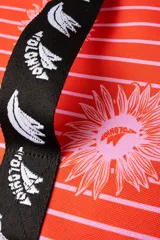 Cooler pequeña con estampado de rayas verticales rojas y flores rosas. Cuenta con manija jacquard en blanco y negro con el monograma Polonio, cierre invisible y interior sellado. Fabricada en poliéster reciclado y aislada con espuma PE laminada en aluminio.