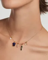 Dije colgante dorado con forma de corazón atravesado por una flecha, con incrustaciones de circonitas blancas.