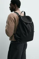 Mochila de cuero con acabado de serraje, cuenta con un compartimento principal con cierre de solapa y cordón ajustable. Incluye asa de mano superior y correas de hombro ajustables.