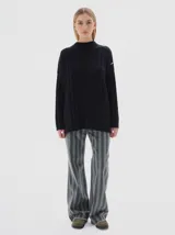 Buzo tejido de punto color beige, con cuello subido, diseño oversized y aberturas laterales en el ruedo.