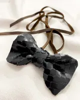 Gargantilla tipo choker con moña de cuero negro y tiento de cuero marrón para atar.