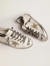 Zapatillas Golden Goose Super-Star de cuero blanco con efecto desgastado, estrella lateral y talón de cuero metalizado dorado, cordones con estampado animal print de leopardo, y detalles manuscritos en la puntera.