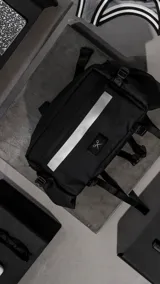 Bolso contenedor negro diseñado para bicicleta, confeccionado en textil de alta resistencia. Cuenta con dos compartimentos independientes con cierres metálicos, dos bolsillos laterales, cinta reflectiva frontal y correas reforzadas para montaje.