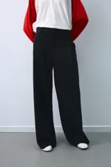 Pantalón de tiro medio color beige, de corte ancho y recto, con pinzas frontales y trabillas en la cintura.