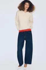 Jersey de punto con cuello tipo polo, manga larga con puños y cierre frontal con botones. Presenta un bolsillo de plastrón en el pecho y diseño de corte holgado.