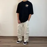 Pantalón de jean estilo cargo con corte baggy, color azul lavado. Presenta cuatro bolsillos laterales de gran tamaño con solapa y cierre de botones, diseño de pierna ancha y tiro medio.