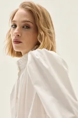 Camisa blanca de popelina elastizada con cuello alto con volados y mangas voluminosas.