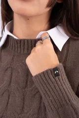 Sweater de punto con diseño de ochos, color marrón, cuello redondo y mangas largas con puños acanalados.
