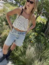 Musculosa blanca con estampado de lunares negros, breteles finos negros y frunce elástico en el busto.