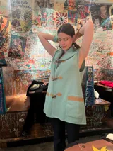 Chaleco verde menta tejido de punto con cuello alto tipo polera, diseño sin mangas, detalles geométricos en tonos tostados y trenza aplicada en la espalda.