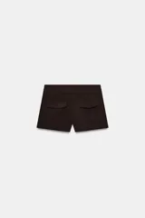 Shorts de tiro medio en color crudo, con bolsillos laterales delanteros y cierre frontal con cremallera y ganchos metálicos.