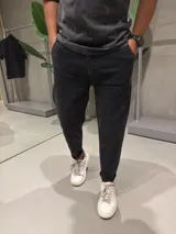 Jean de corte slouchy en color negro con efecto gastado. Presenta un diseño de tiro medio, ajuste holgado en la cadera y piernas que se estrechan hacia el tobillo.