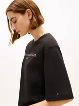 Remera negra de corte amplio de la marca Tommy Hilfiger, confeccionada en punto de puro algodón. Presenta cuello redondo, mangas cortas y anchas con hombros ligeramente caídos, y el logo de la marca estampado en el pecho en color blanco.