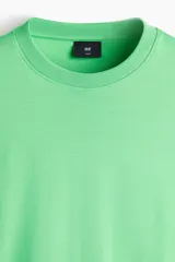 Remera boxy de algodón en color verde, con hombros caídos, cuello redondo acanalado y corte oversized.