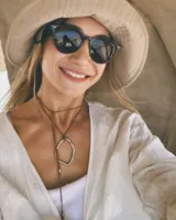 Collar con dije colgante de forma orgánica e irregular, acabado dorado, suspendido de un cordón negro de algodón natural.