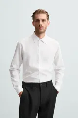 Camisa blanca de manga larga con cuello italiano y cierre frontal de botonadura. Corte regular fit.