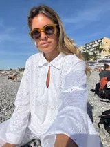 Camisa blanca de broderie con cuello camisero, mangas largas y cierre frontal con botones.