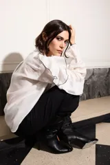 Camisa blanca con volados con terminación de hilo negro en cuello, mangas y frente.