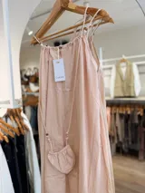 Vestido midi celeste de silueta amplia y fluida, con escote fruncido y tirantes finos decorados con cuentas de madera. Incluye una pequeña carterita colgante haciendo juego.