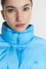 Campera puffer acolchada de color azul brillante, con cuello alto y cierre frontal mediante botones a presión. Diseño de corte estándar con costuras horizontales.