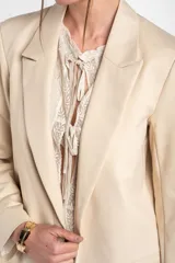 Blazer de algodón peinado, color beige, de calce al cuerpo con solapas clásicas y mangas largas.