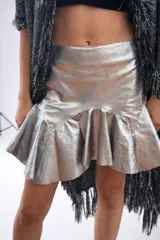 Minifalda de cuero sintético color plateado metalizado, con cintura alta y un volante fruncido en el ruedo inferior.