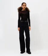 Pantalón de jean corte wide leg, color negro, con cintura media y detalle de ojales metálicos en el cós. Presenta piernas amplias, cierre tradicional y bolsillos funcionales.