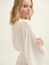 Bata kimono blanca, de tejido liviano y semitransparente con textura de lunares en relieve. Posee mangas amplias estilo murciélago y un lazo para atar a la cintura.