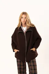 Tapado tipo poncho de silueta oversize, color marrón, confeccionado en paño. Presenta cuello alto con cierre frontal de cremallera niquelada, mangas anchas y bolsillos laterales.