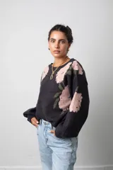 Buzo de punto color negro con estampado floral en tonos rosado y verde, de corte oversize, cuello redondo y mangas globo.