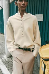 Jersey de punto color marrón, de cuello redondo y manga larga, con cierre frontal parcial de botones.