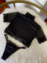 Conjunto de lencería compuesto por un top de cuello alto con mangas de microtul y detalles de encaje, y una tanga regulable a juego. El diseño combina lycra, microtul y encaje elastizado en color negro.