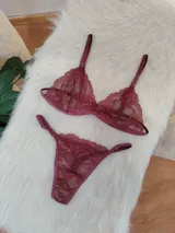 Conjunto de lencería de encaje bordó, compuesto por un corpiño triangular con breteles regulables y una bombacha tipo tanga con laterales ajustables.